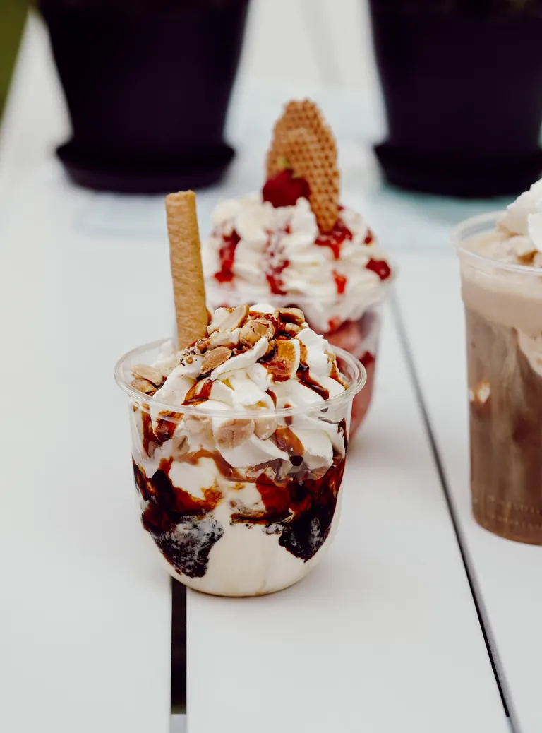 Zwei Eisbecher und ein Eiskaffee auf dem Gartentisch im Il Colosseo